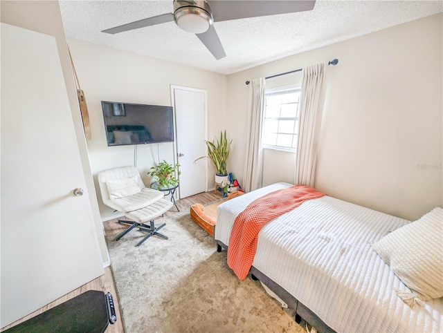 bedroom featuring hardwood / wood-style floors, a textured ceiling, and ceiling fan