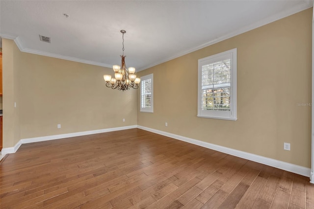 spare room featuring wood-type flooring, a notable chandelier, and ornamental molding