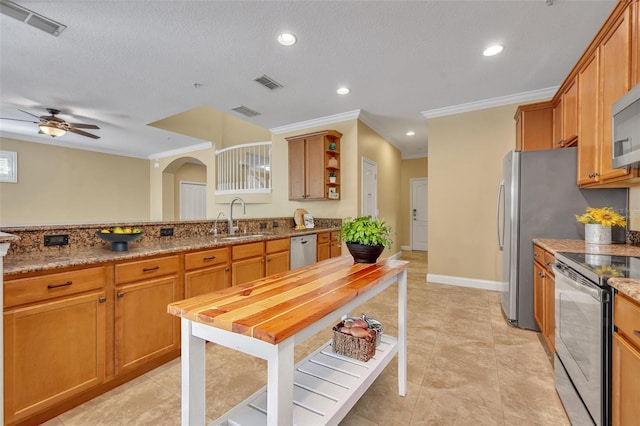 kitchen with stainless steel appliances, light stone countertops, a textured ceiling, and sink