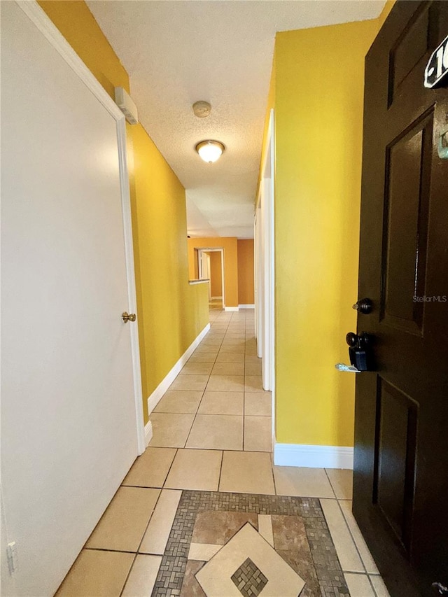 corridor featuring a textured ceiling and light tile patterned flooring