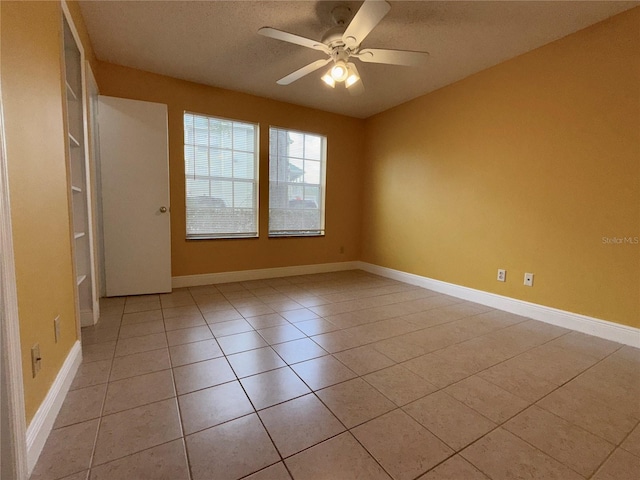 tiled empty room with ceiling fan and a textured ceiling