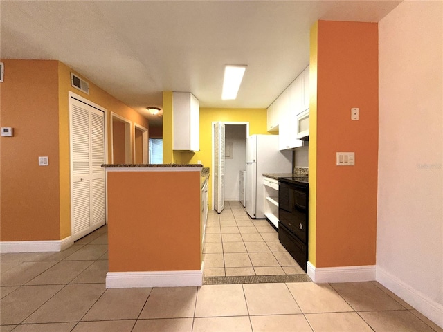 kitchen with white cabinets, kitchen peninsula, light tile patterned flooring, and white fridge