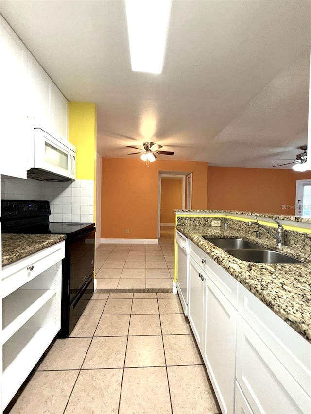 kitchen featuring sink, dark stone countertops, light tile patterned floors, white appliances, and white cabinets