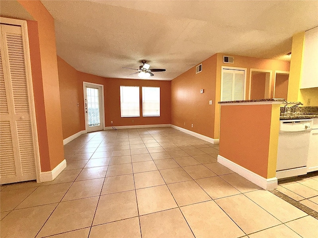 unfurnished living room with ceiling fan, a textured ceiling, light tile patterned floors, and sink