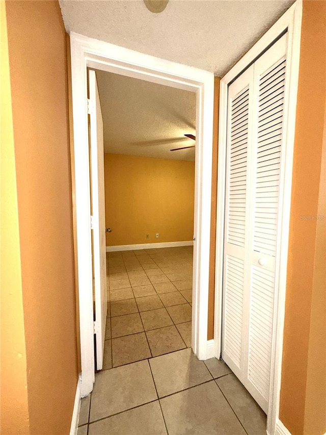 hallway with a textured ceiling and light tile patterned floors