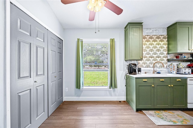 kitchen featuring backsplash, white dishwasher, ceiling fan, light hardwood / wood-style floors, and green cabinets