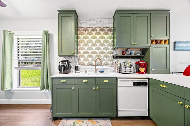 kitchen with tasteful backsplash, white dishwasher, sink, light hardwood / wood-style floors, and green cabinets