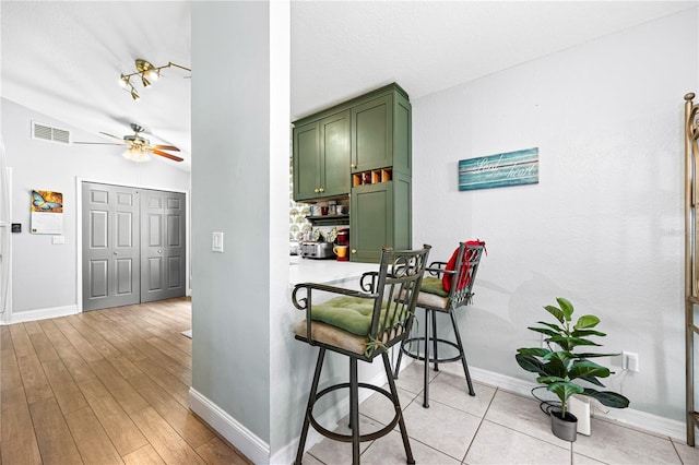 interior space featuring green cabinets, ceiling fan, light hardwood / wood-style floors, and vaulted ceiling