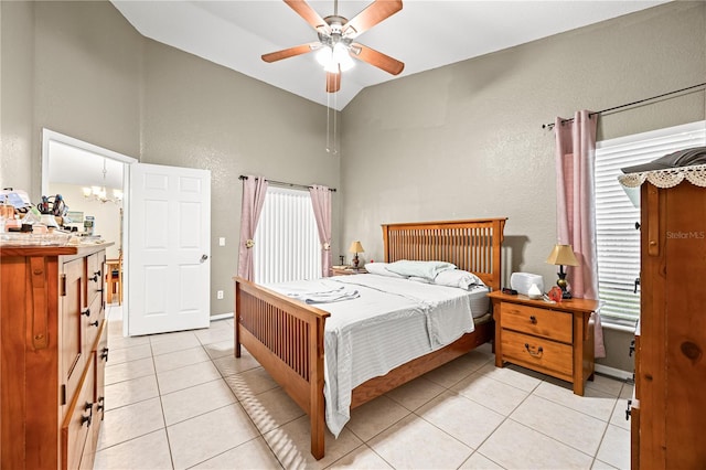 tiled bedroom with ceiling fan with notable chandelier, multiple windows, and lofted ceiling