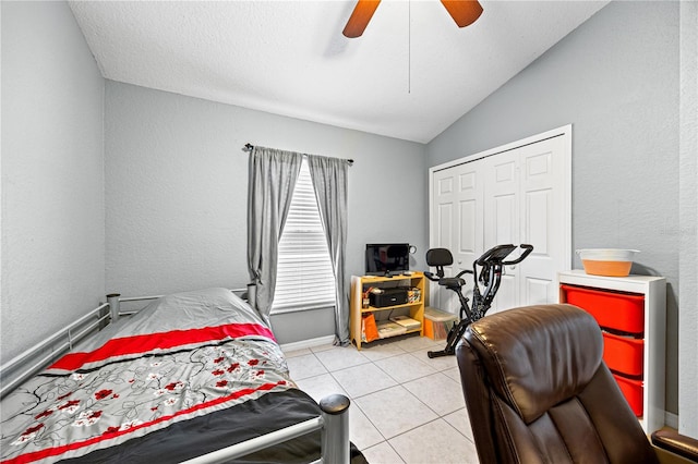 bedroom with ceiling fan, a textured ceiling, lofted ceiling, a closet, and light tile patterned floors