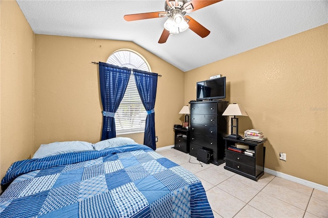 bedroom with a textured ceiling, ceiling fan, light tile patterned flooring, and lofted ceiling