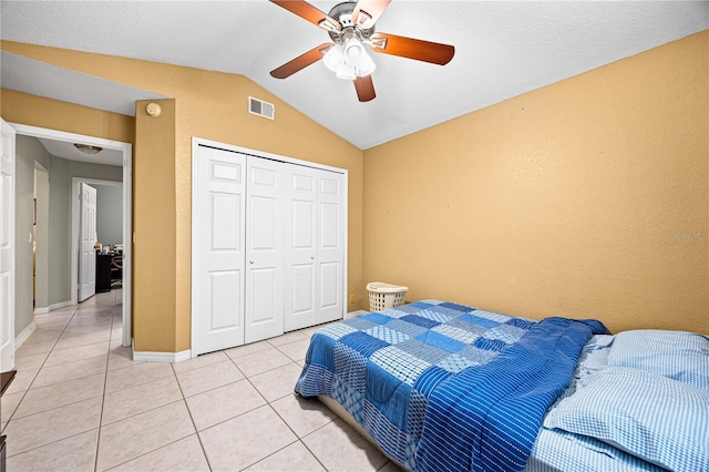 bedroom featuring ceiling fan, vaulted ceiling, light tile patterned floors, and a closet