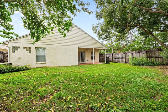 rear view of property featuring a yard and ceiling fan