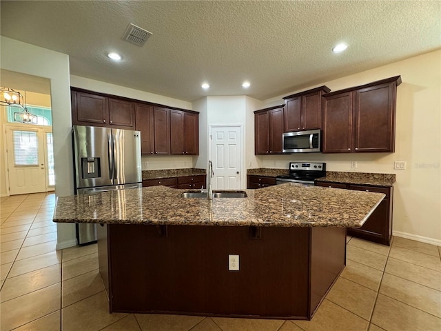 kitchen with a center island with sink, sink, appliances with stainless steel finishes, a kitchen bar, and a textured ceiling