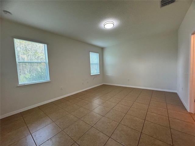 tiled empty room with a textured ceiling