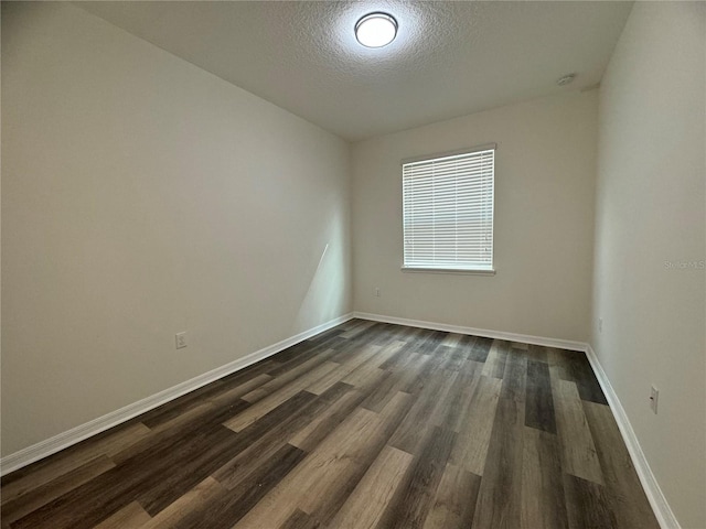 empty room with dark wood-type flooring, a textured ceiling, and lofted ceiling