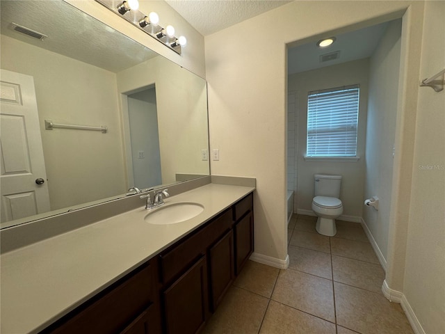 bathroom with toilet, vanity, a textured ceiling, and tile patterned floors