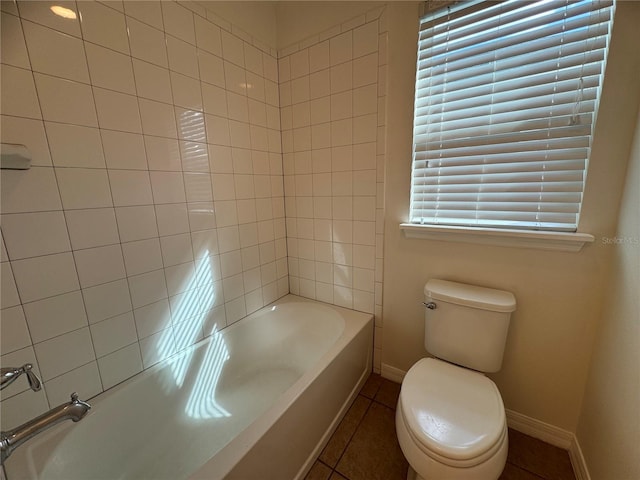 bathroom with tile patterned flooring, toilet, and tiled shower / bath combo