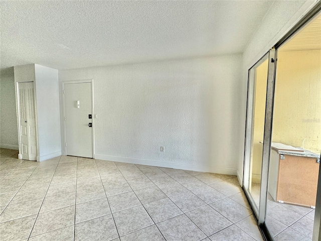 tiled empty room featuring a textured ceiling