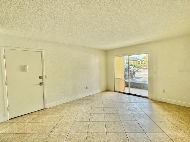 tiled empty room featuring a textured ceiling