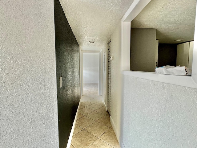 hallway featuring a textured ceiling and light tile patterned floors