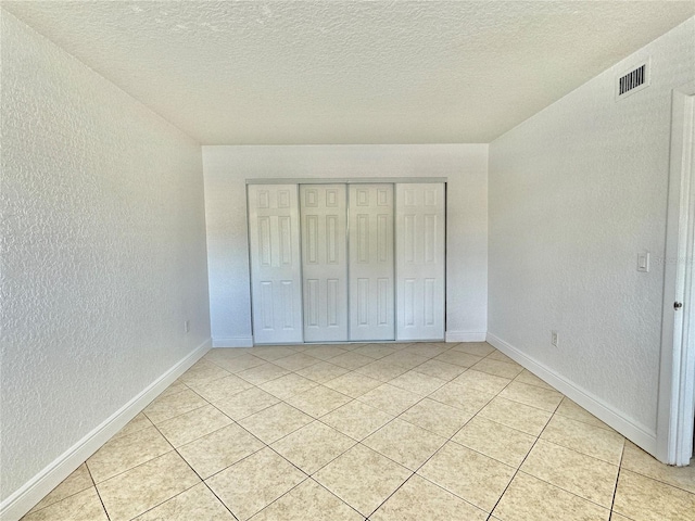 unfurnished bedroom featuring light tile patterned floors, a textured ceiling, and a closet