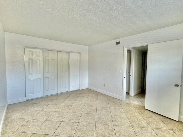 unfurnished bedroom with light tile patterned flooring, a textured ceiling, and a closet