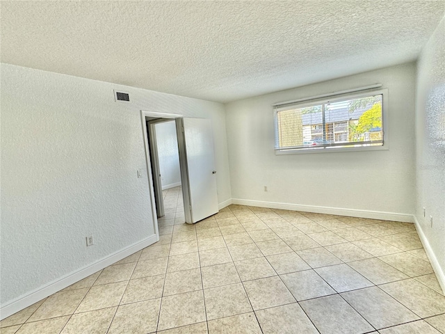 tiled empty room featuring a textured ceiling