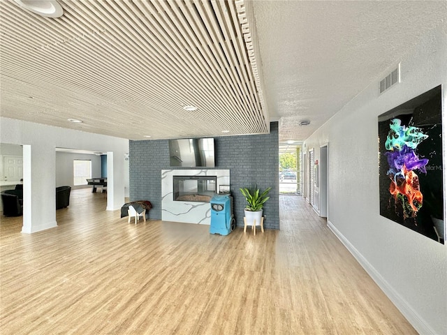 living room with a fireplace, light hardwood / wood-style floors, and a textured ceiling