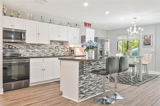 kitchen featuring white cabinets, stainless steel appliances, a kitchen island, and light hardwood / wood-style floors