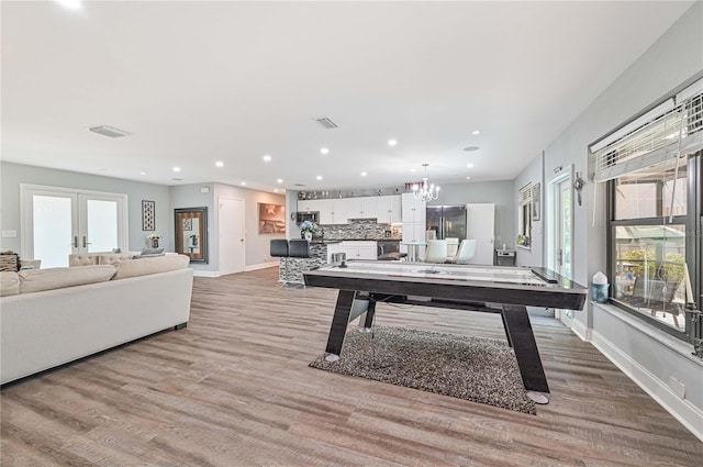 playroom with a chandelier, french doors, and light wood-type flooring