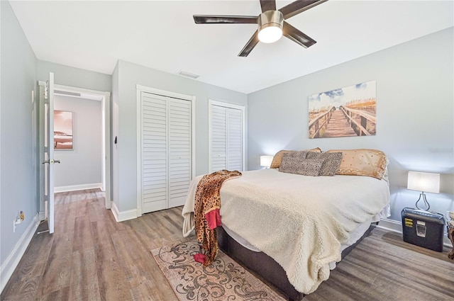 bedroom with light hardwood / wood-style floors, ceiling fan, and multiple closets