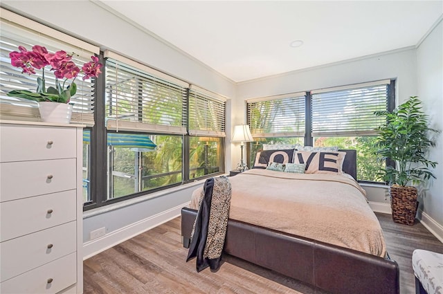 bedroom with multiple windows, crown molding, and hardwood / wood-style flooring