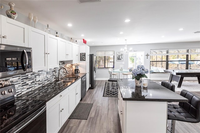 kitchen featuring electric range oven, decorative light fixtures, sink, a kitchen breakfast bar, and a center island