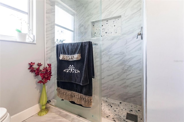 bathroom with a tile shower and toilet