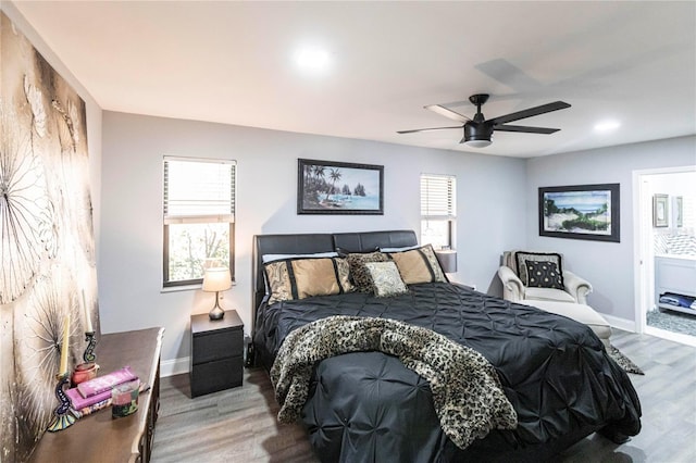 bedroom with hardwood / wood-style flooring, ensuite bath, ceiling fan, and multiple windows