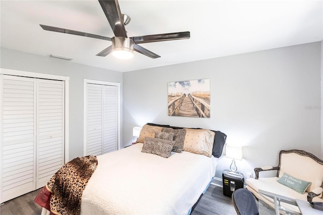 bedroom featuring dark wood-type flooring, two closets, and ceiling fan