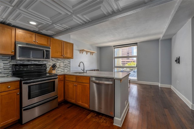 kitchen featuring kitchen peninsula, appliances with stainless steel finishes, dark hardwood / wood-style flooring, backsplash, and sink