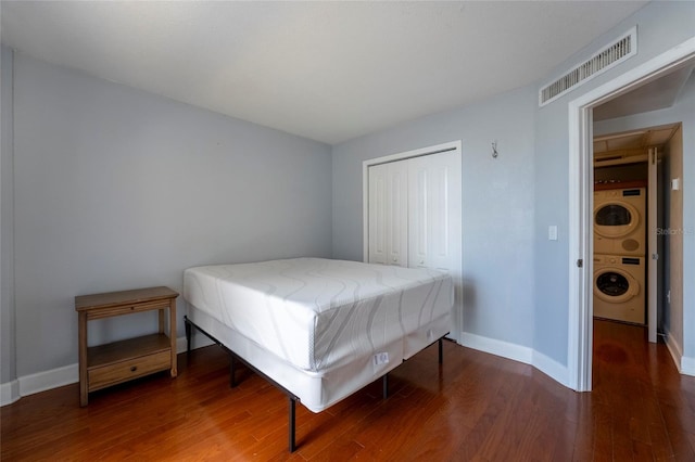 bedroom featuring a closet, stacked washing maching and dryer, and dark hardwood / wood-style floors