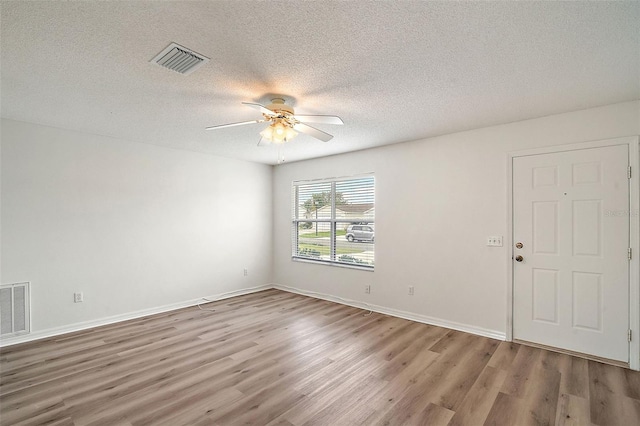 empty room featuring light hardwood / wood-style floors, ceiling fan, and a textured ceiling