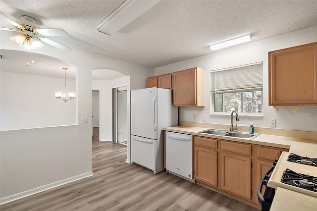 kitchen with ceiling fan with notable chandelier, light hardwood / wood-style floors, sink, white appliances, and decorative light fixtures