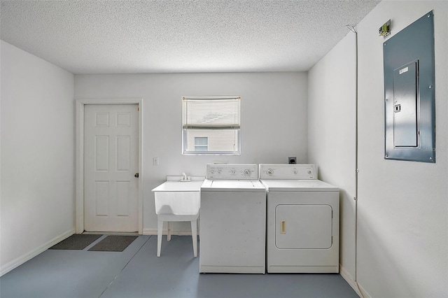 washroom with electric panel, a textured ceiling, and washing machine and dryer