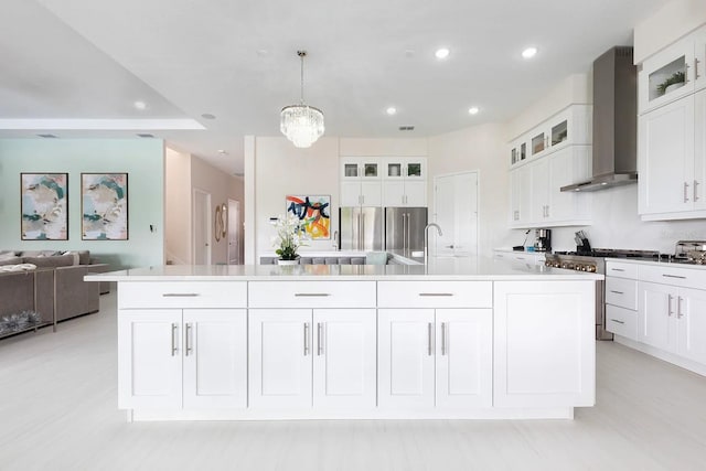 kitchen with stainless steel appliances, white cabinetry, wall chimney exhaust hood, a spacious island, and pendant lighting