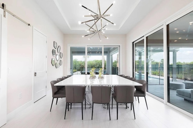 dining area with a wealth of natural light, a notable chandelier, a barn door, and a tray ceiling