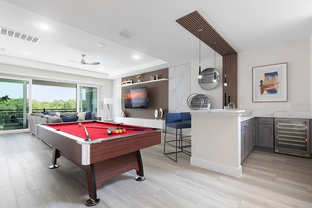 playroom with ceiling fan, beverage cooler, a raised ceiling, light hardwood / wood-style flooring, and billiards