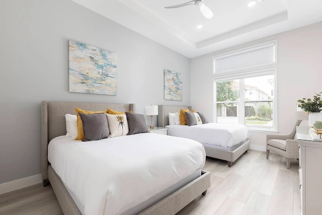 bedroom featuring light wood-type flooring, ceiling fan, and a raised ceiling