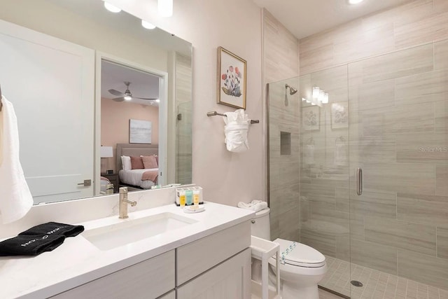 bathroom with vanity, ceiling fan, toilet, and a shower with shower door