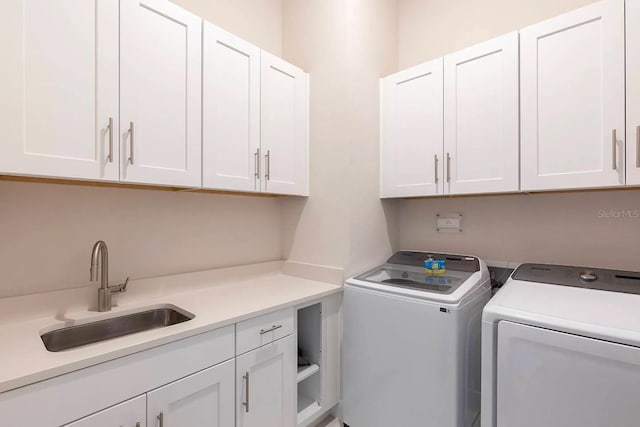 washroom with cabinets, sink, and washing machine and clothes dryer