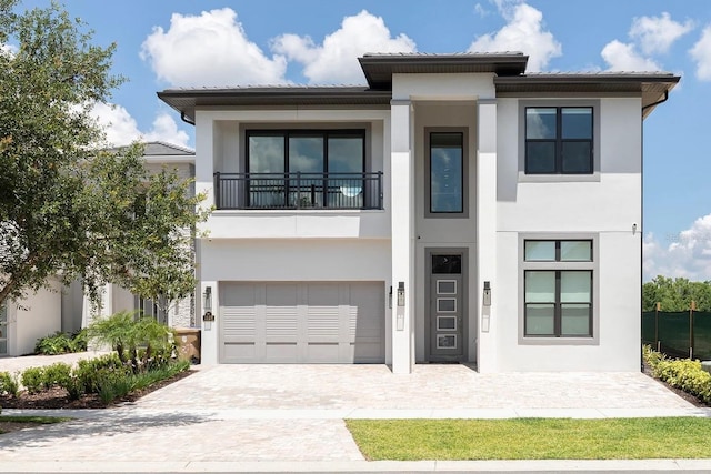 view of front of property with a garage, a balcony, decorative driveway, and stucco siding