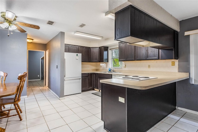 kitchen with dark brown cabinetry, kitchen peninsula, ceiling fan, light tile patterned floors, and white appliances